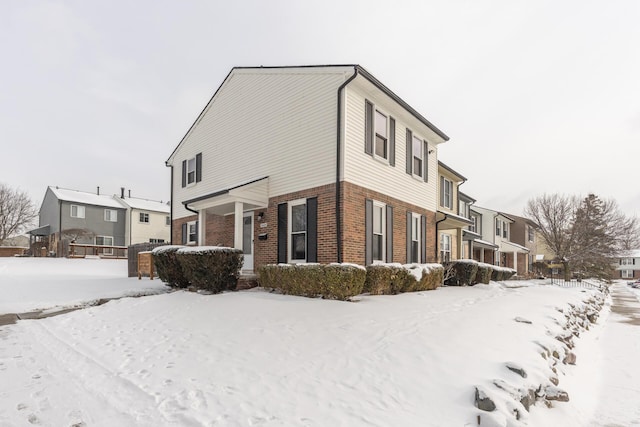 view of snowy exterior featuring a residential view and brick siding