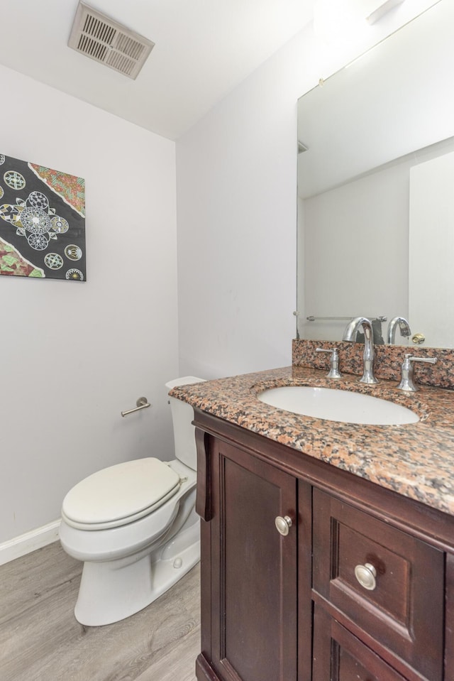 bathroom featuring toilet, wood finished floors, vanity, visible vents, and baseboards