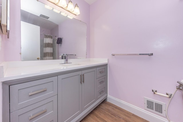 bathroom featuring curtained shower, visible vents, vanity, wood finished floors, and baseboards