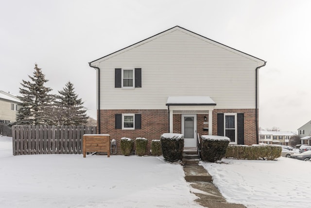 traditional home featuring fence and brick siding