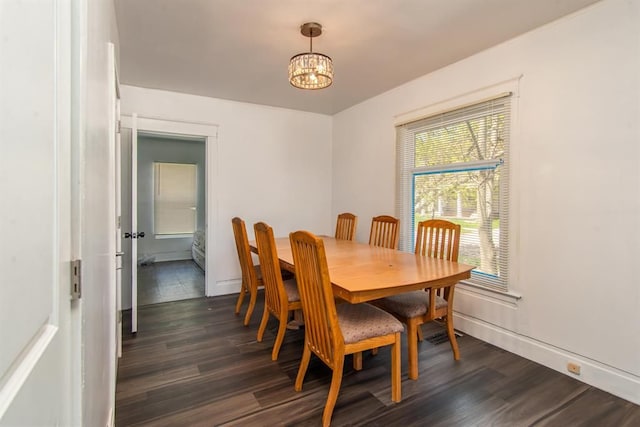 dining area featuring baseboards, dark wood-type flooring, and a notable chandelier