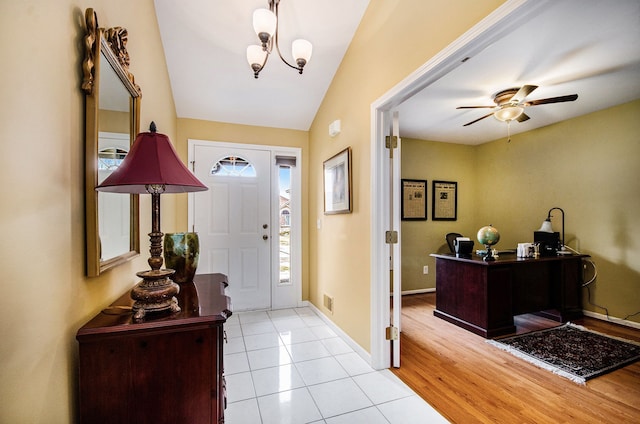 tiled entrance foyer featuring lofted ceiling, visible vents, baseboards, and ceiling fan with notable chandelier