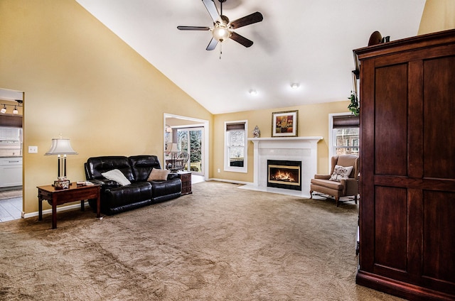 carpeted living area featuring ceiling fan, high vaulted ceiling, a fireplace with flush hearth, and baseboards