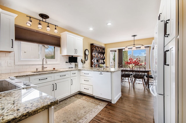 kitchen featuring dark wood-style floors, white cabinets, a sink, white appliances, and a peninsula