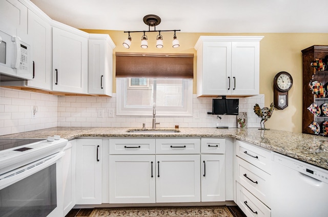 kitchen with decorative backsplash, white cabinetry, a sink, light stone countertops, and white appliances