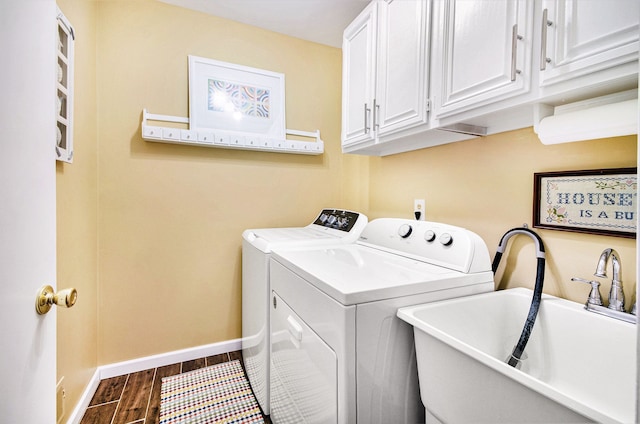 washroom with wood finished floors, a sink, baseboards, cabinet space, and washer and clothes dryer