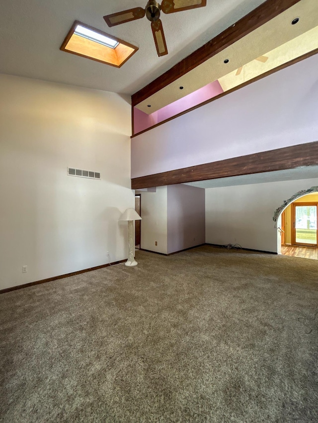 unfurnished room with a ceiling fan, a skylight, carpet flooring, and visible vents