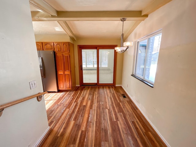 unfurnished dining area featuring visible vents, lofted ceiling with beams, an inviting chandelier, wood finished floors, and baseboards