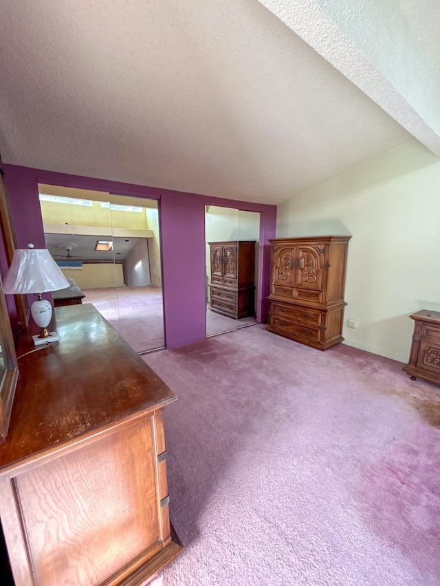 bedroom featuring light colored carpet, a textured ceiling, and two closets