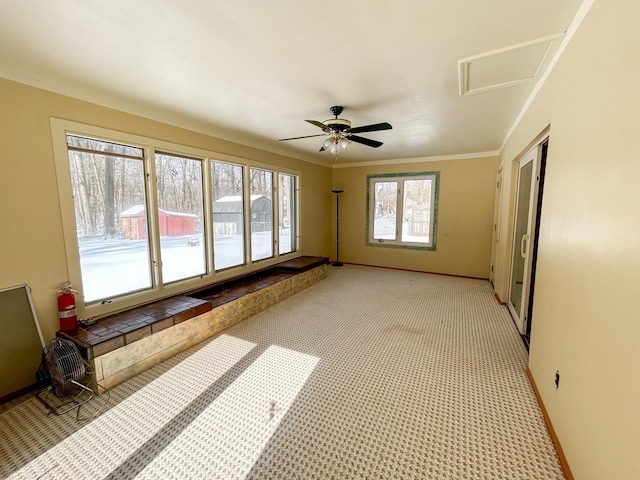 interior space with baseboards, light carpet, a ceiling fan, and crown molding