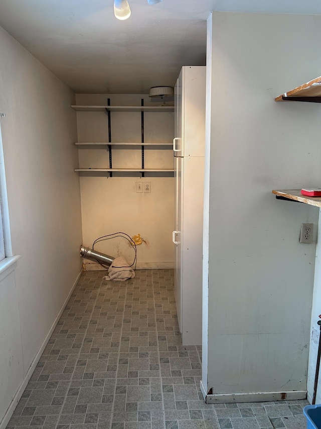 laundry area with brick floor and baseboards