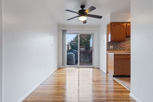 doorway to outside with baseboards, ceiling fan, and light wood-style floors