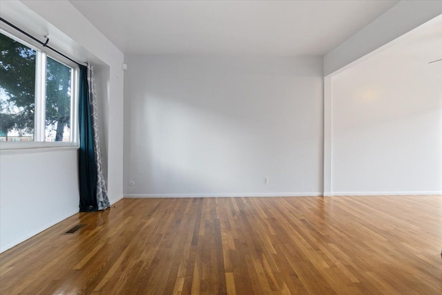 unfurnished room featuring visible vents, baseboards, and wood finished floors