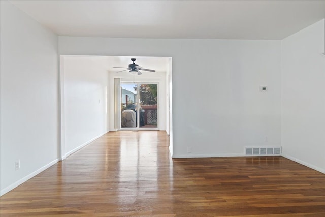 spare room featuring dark wood-style floors, visible vents, baseboards, and a ceiling fan