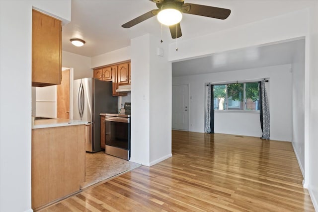 kitchen with brown cabinets, stainless steel appliances, light countertops, light wood-style floors, and under cabinet range hood