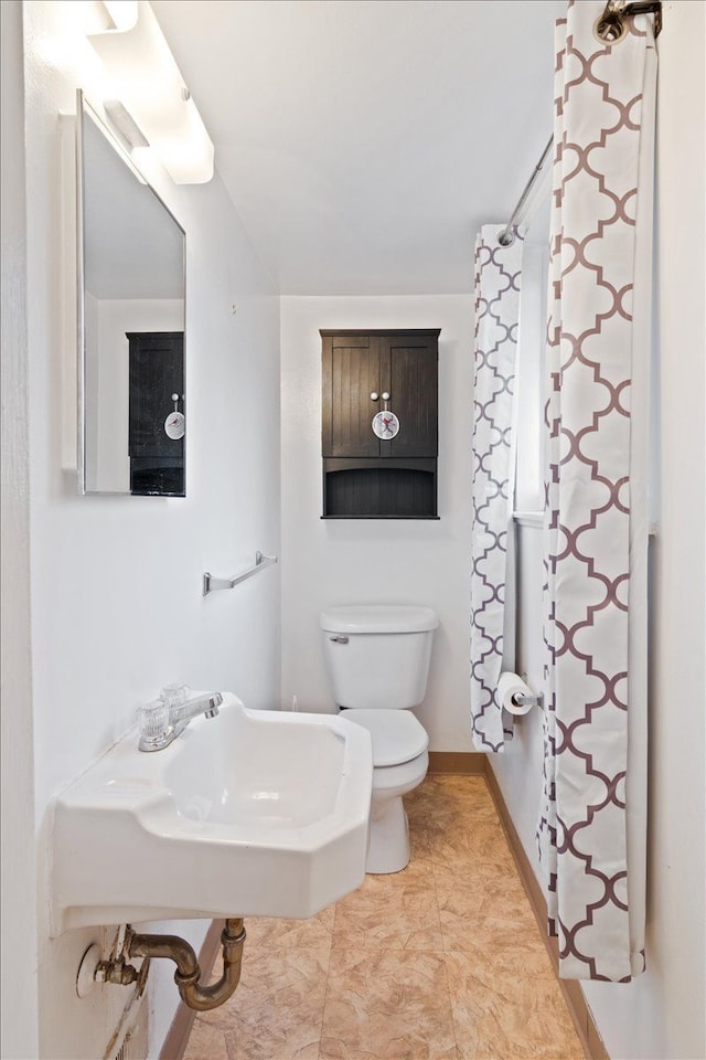 full bathroom featuring toilet, baseboards, and a sink