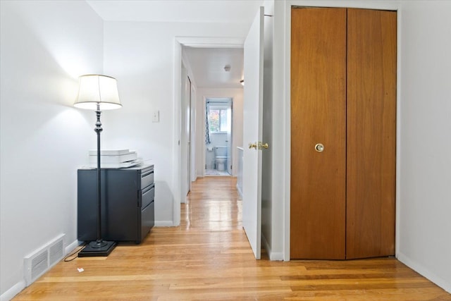 hall with visible vents, light wood-style flooring, and baseboards