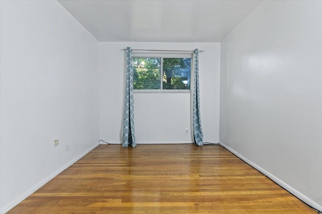 spare room with baseboards and wood finished floors