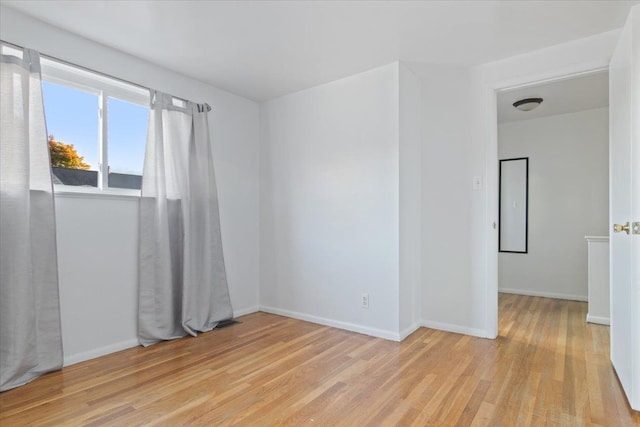 empty room featuring light wood-type flooring and baseboards