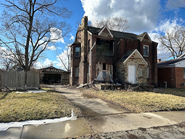 view of front of house featuring brick siding, a chimney, a front yard, fence, and stone siding