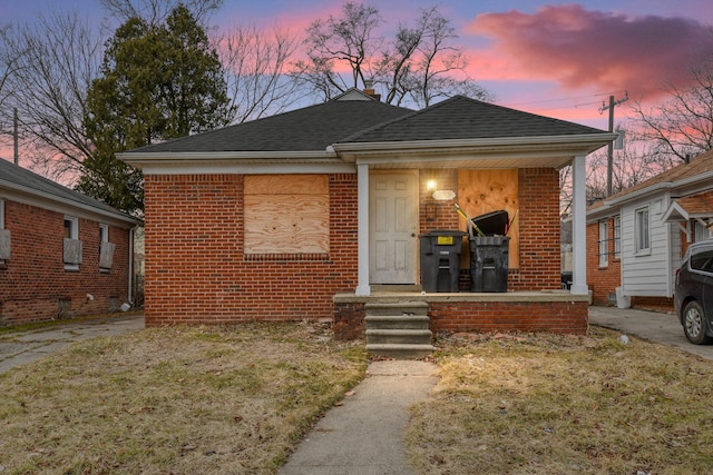 bungalow-style house featuring a porch, brick siding, and a shingled roof