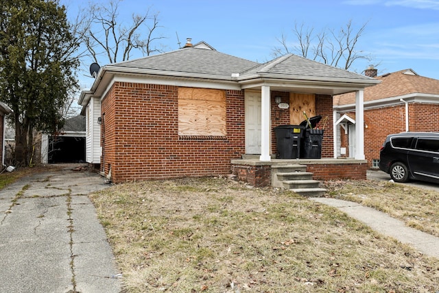 view of front of property featuring brick siding, a porch, and a shingled roof