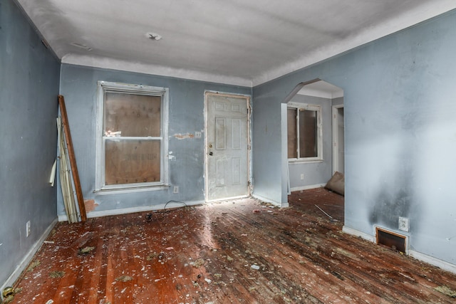 unfurnished room featuring baseboards and arched walkways