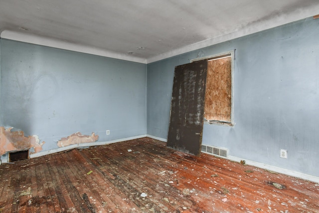 empty room with visible vents, baseboards, and wood finished floors