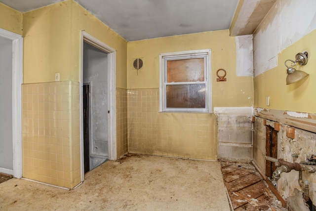 bathroom featuring a wainscoted wall and tile walls