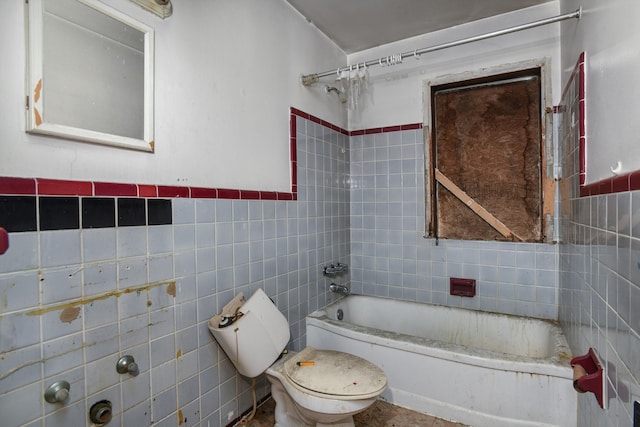 bathroom with tile walls, toilet, washtub / shower combination, and a wainscoted wall