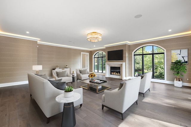 living room featuring a lit fireplace, baseboards, and crown molding