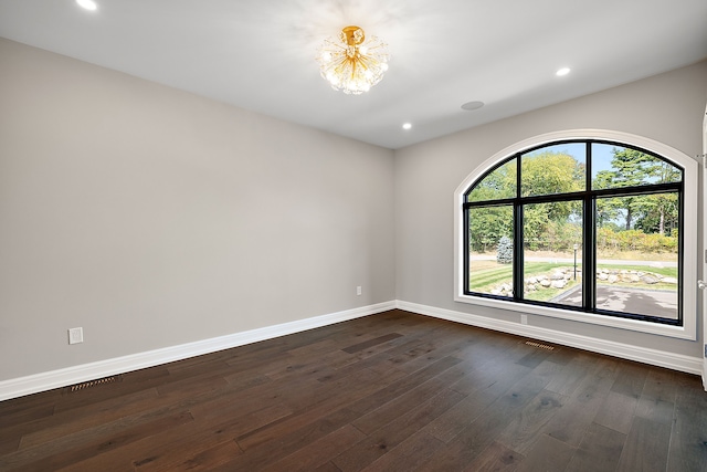 empty room featuring dark wood-style floors, recessed lighting, visible vents, an inviting chandelier, and baseboards