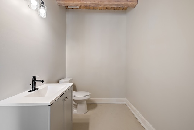 half bathroom with finished concrete floors, baseboards, vanity, and toilet