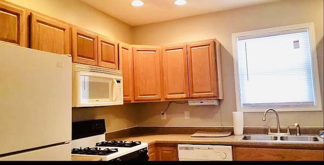 kitchen featuring white appliances, brown cabinetry, a sink, and recessed lighting