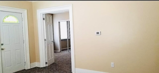 hall with dark colored carpet and baseboards