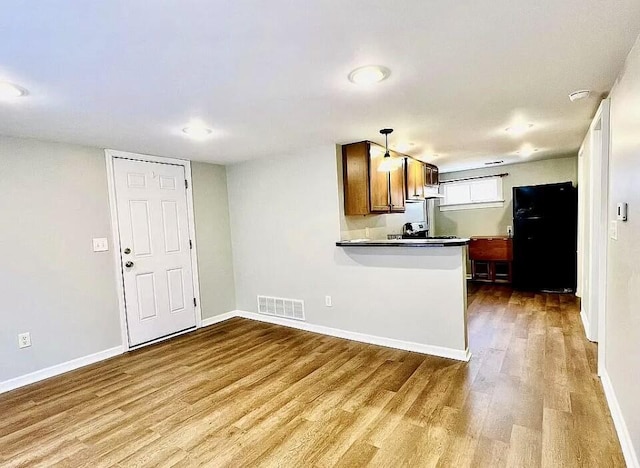 kitchen with light wood finished floors, visible vents, brown cabinetry, white cabinetry, and a peninsula