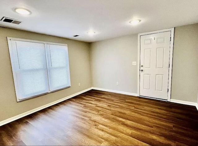 spare room featuring visible vents, baseboards, and wood finished floors