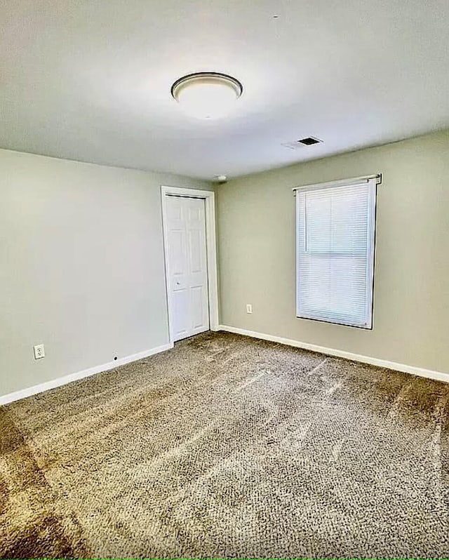 empty room featuring carpet floors and baseboards