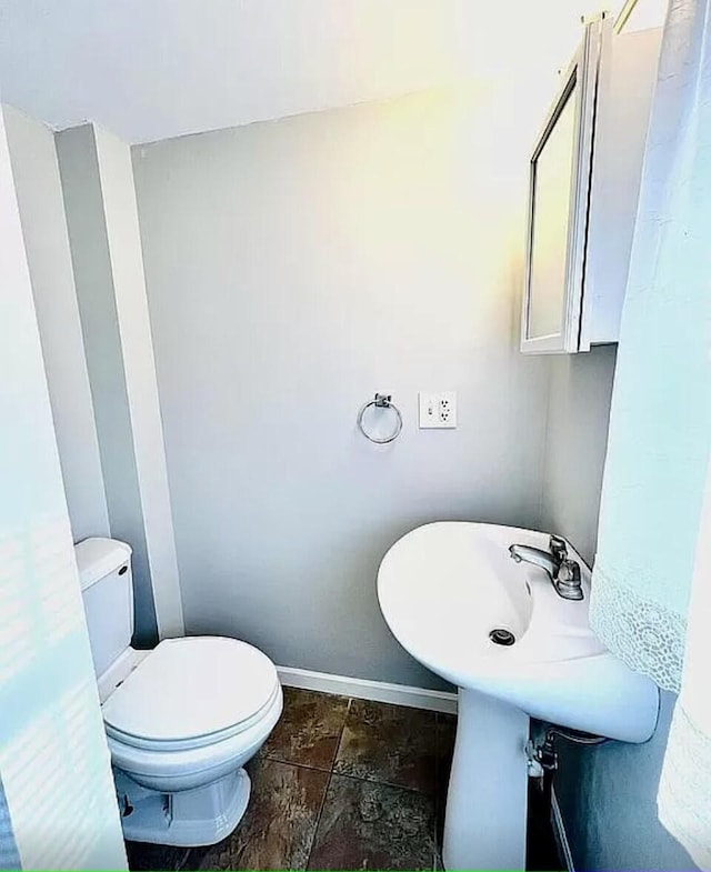 half bath featuring toilet and baseboards