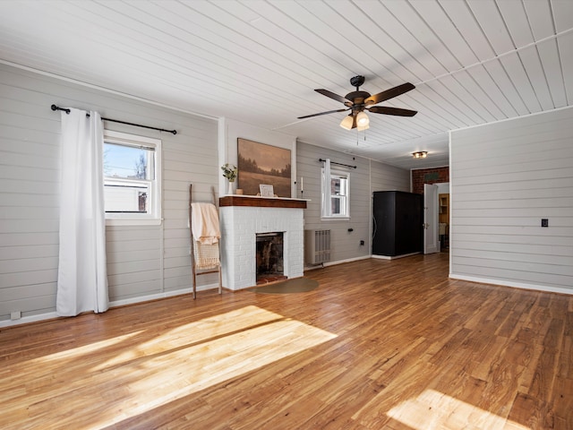 unfurnished living room with wooden ceiling, a brick fireplace, a ceiling fan, and wood finished floors