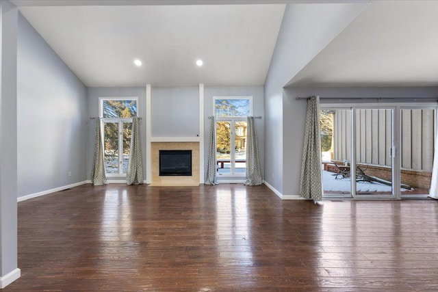 unfurnished living room featuring a fireplace with flush hearth, lofted ceiling, dark wood-type flooring, and baseboards