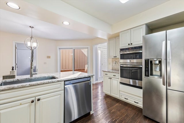 kitchen featuring dark wood-style floors, stainless steel appliances, decorative light fixtures, and light stone countertops