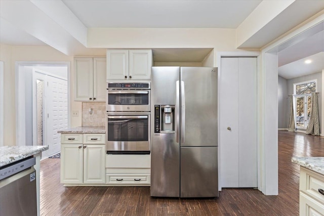 kitchen featuring tasteful backsplash, light stone counters, stainless steel appliances, and dark wood-style flooring