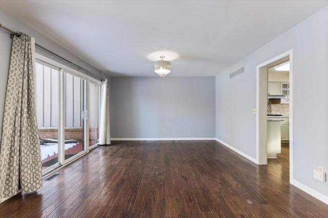 unfurnished room with baseboards, visible vents, and wood finished floors