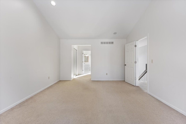 interior space with lofted ceiling, visible vents, light carpet, and baseboards