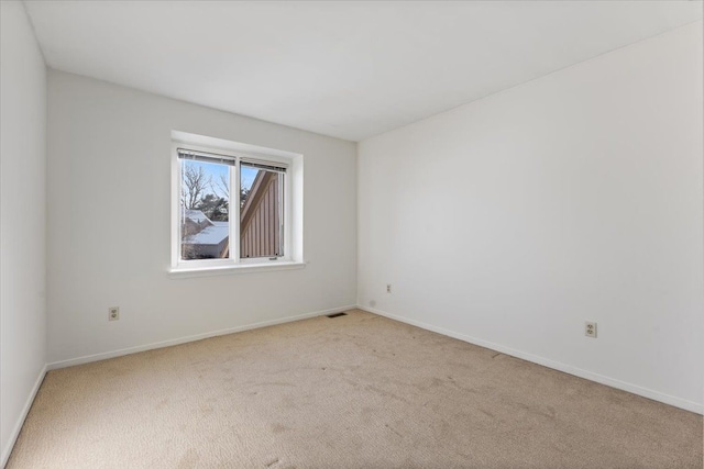 spare room featuring light carpet, visible vents, and baseboards