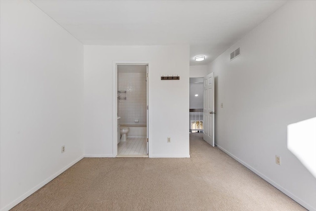 unfurnished bedroom with ensuite bath, baseboards, visible vents, and light colored carpet