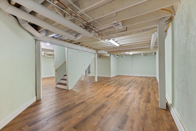 finished basement featuring wood finished floors, baseboards, and stairs