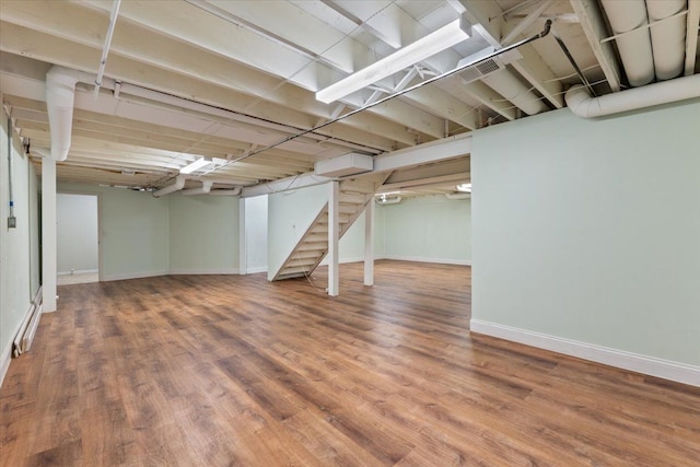 finished below grade area with stairs, baseboards, and wood finished floors