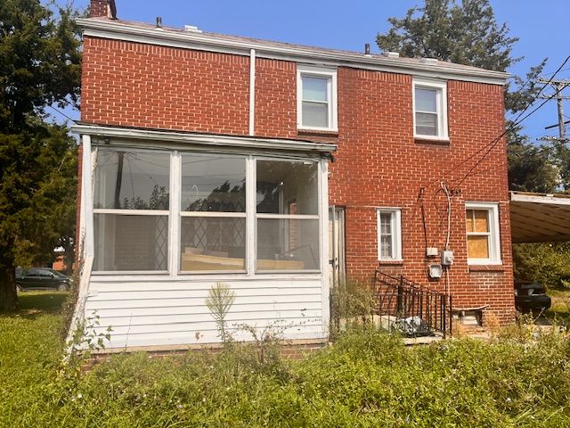 back of house with a sunroom and brick siding